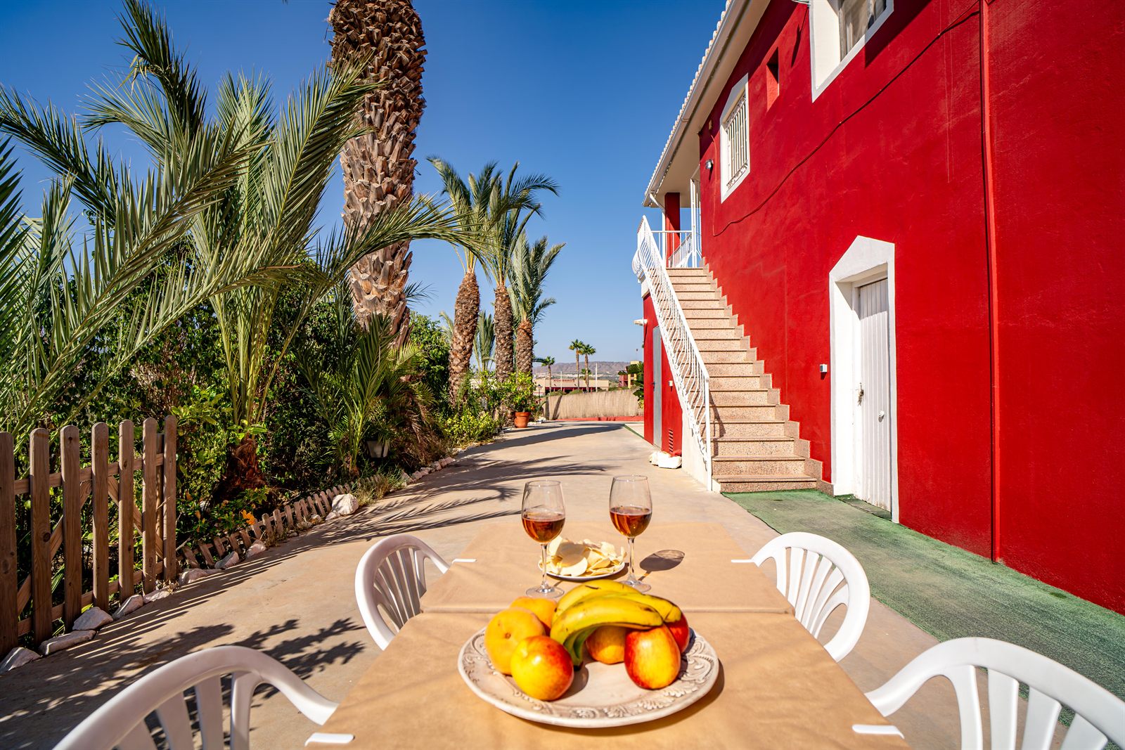 Fachada roja de Villa Adelina con terraza y palmeras