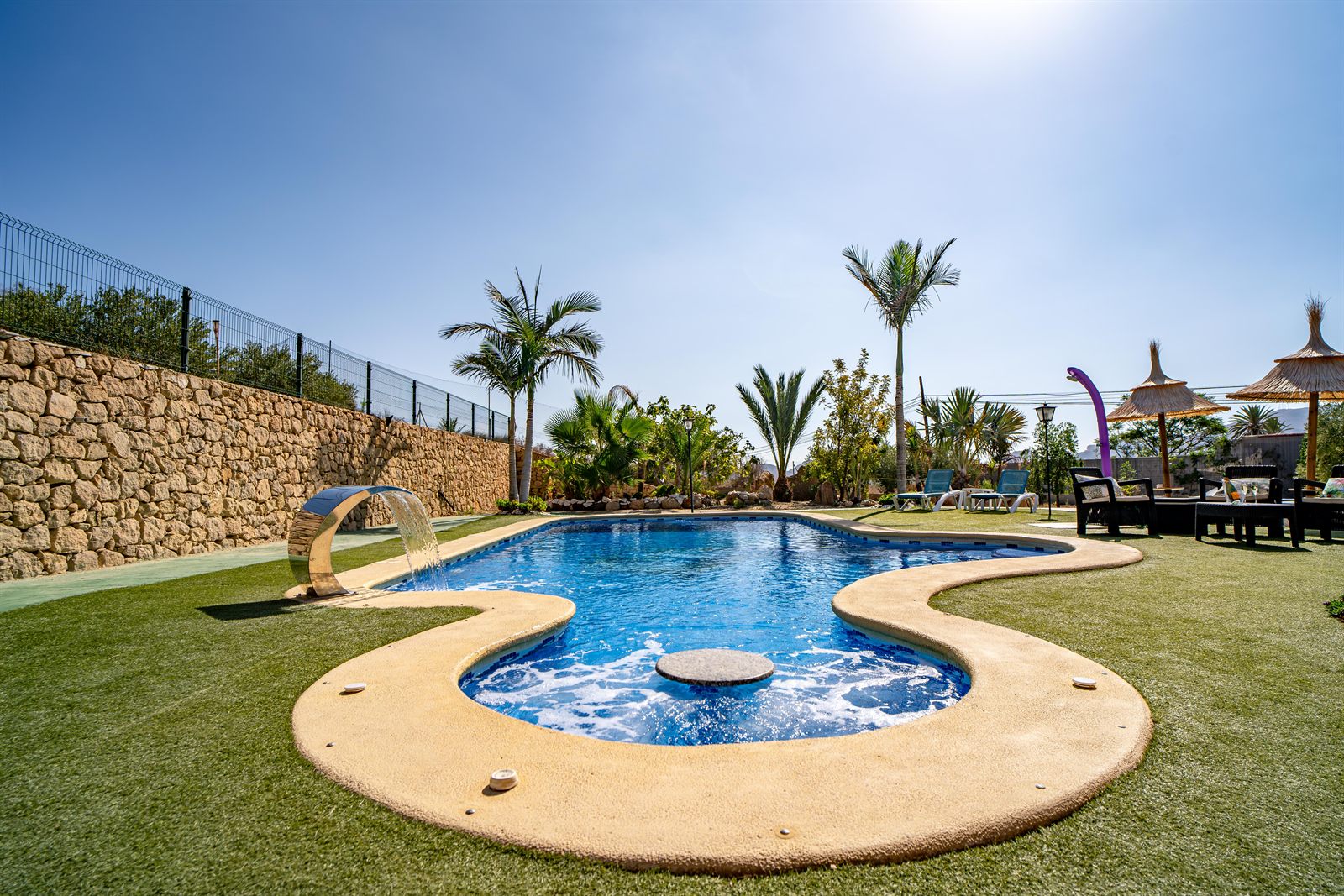 Piscina privada con cascada y zona de hidromasaje